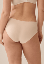 Achterzijde van vrouw die de one size slip in de kleur beige van het merk Naturana draagt