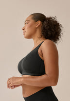 Zijde van vrouw die de prothese bh in de kleur zwart van het merk Naturana draagt