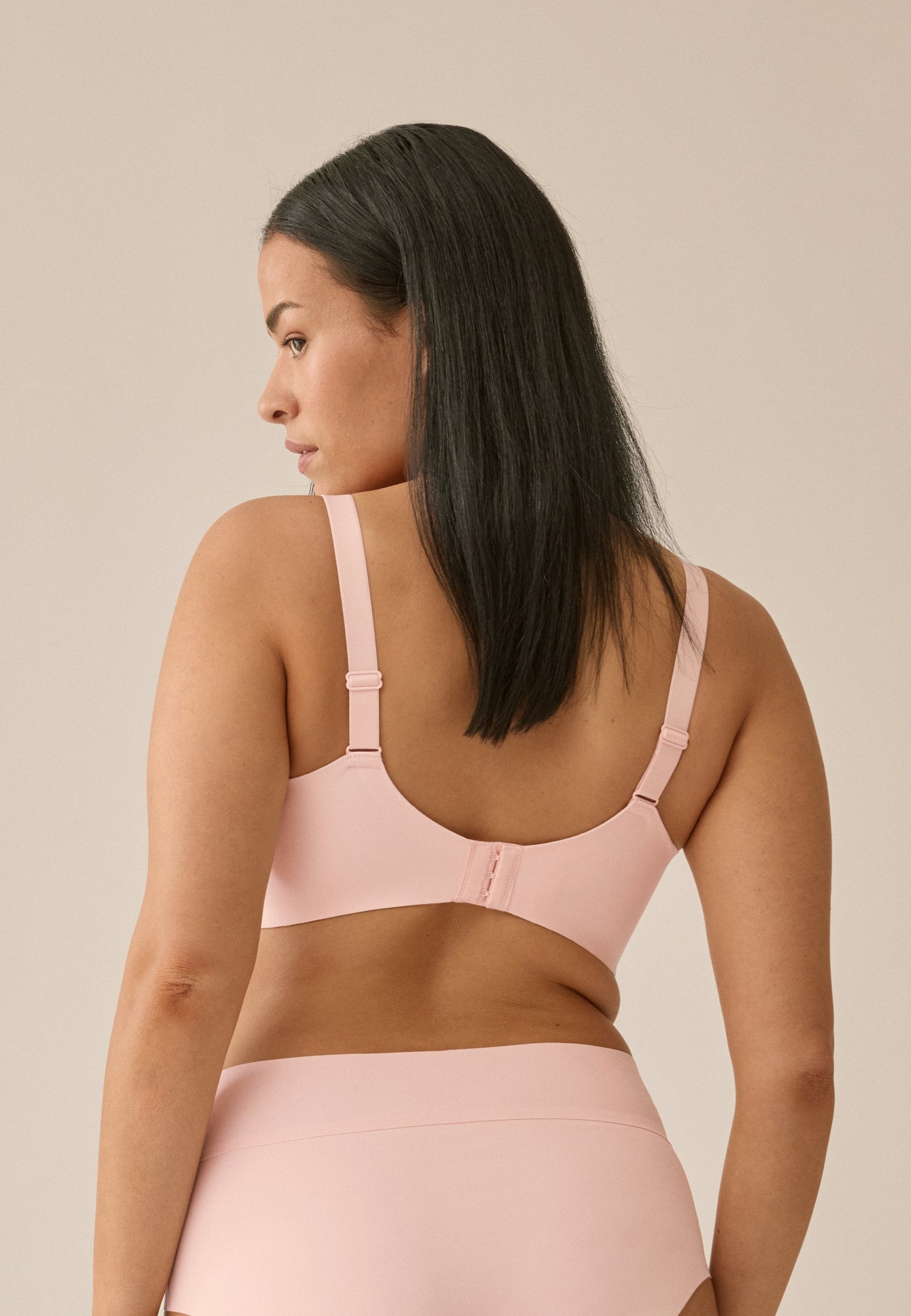 Achterzijde van vrouw die de side smoother bh in de kleur blush van het merk Naturana draagt