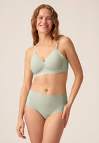 Voorzijde van vrouw die de side smoother bh en de high waist slip in de kleur pale greenshield van het merk Naturana draagt
