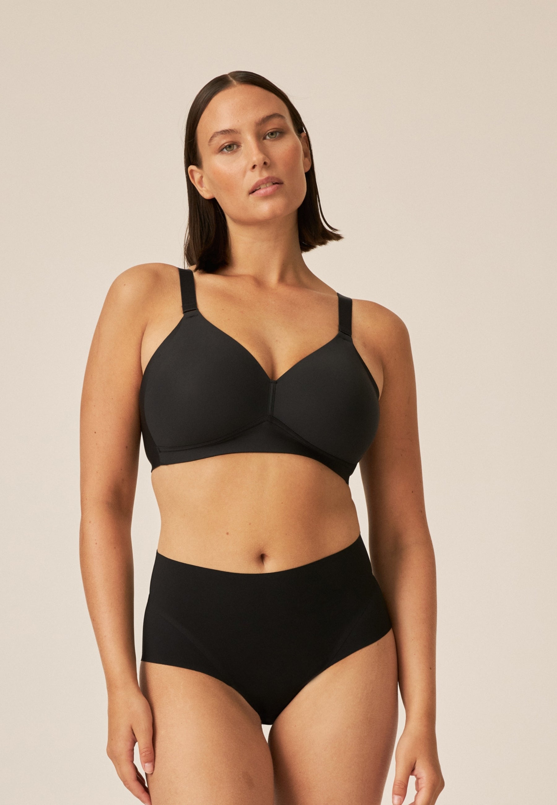 Voorzijde van vrouw die de side smoother bh en high waist slip in de kleur zwart van het merk Naturana draagt
