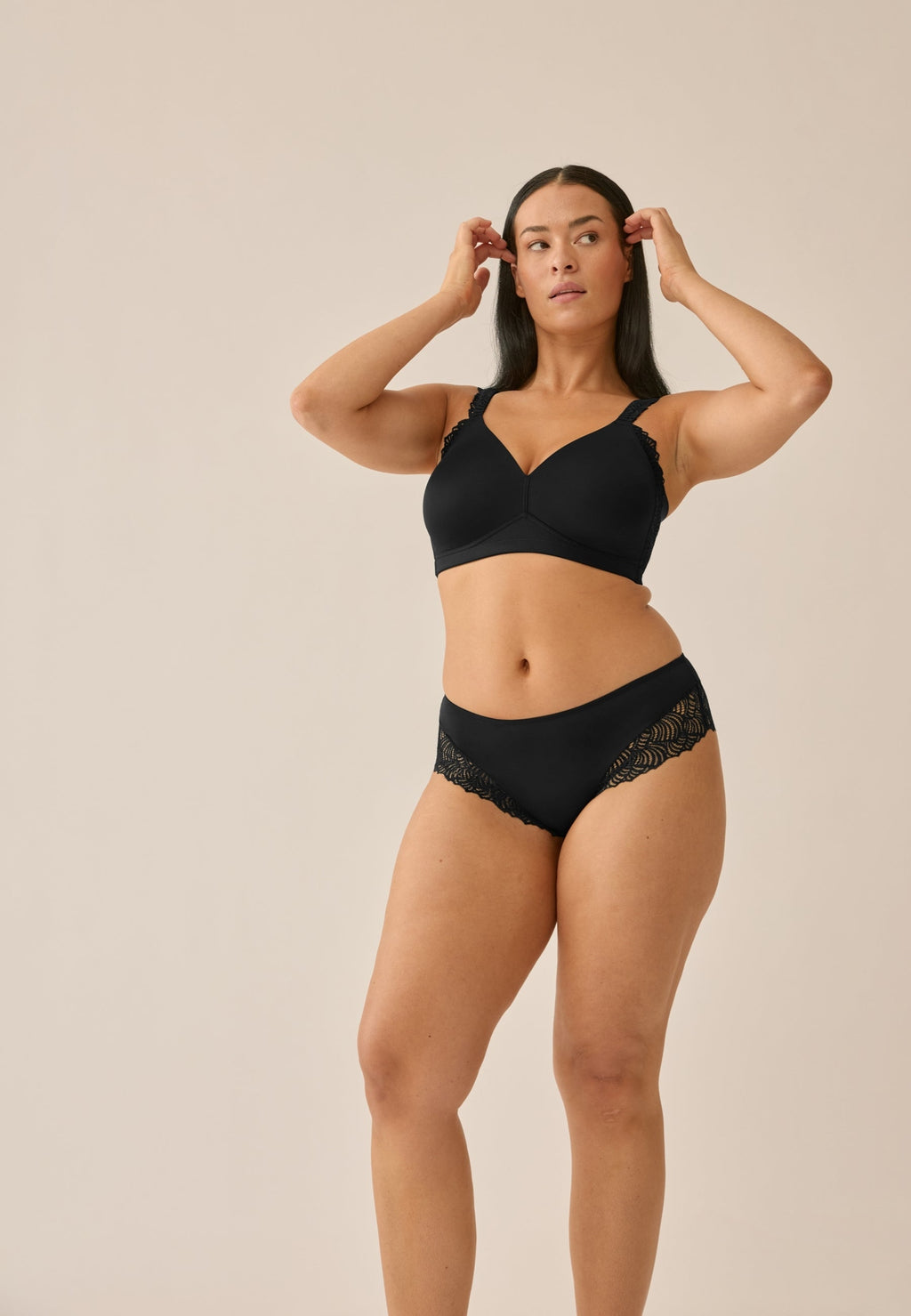 Voorzijde van vrouw die de side smoother bh en hipster met gerecycled kant in de kleur zwart van het merk Naturana draagt