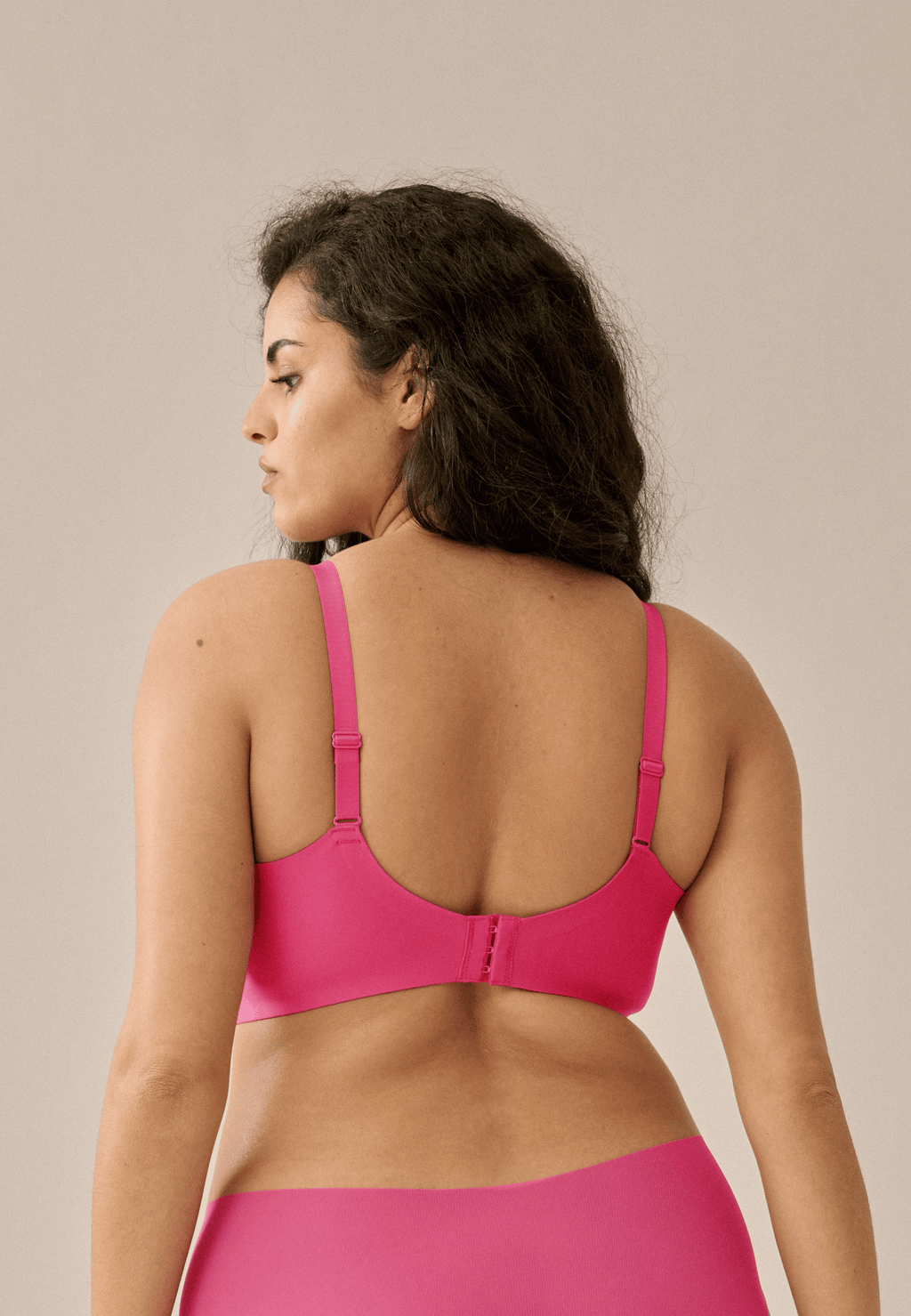 Achterzijde van vrouw die de side smoother bh in de kleur hot pink van het merk Naturana draagt