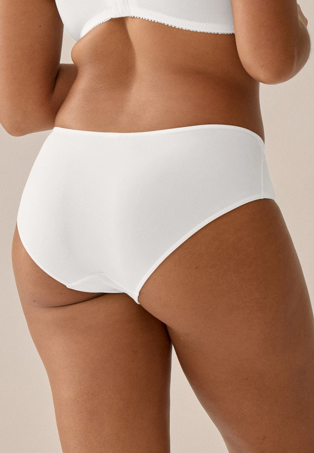 Achterzijde van vrouw die de slip met glansband in de kleur ecru van het merk Naturana draagt