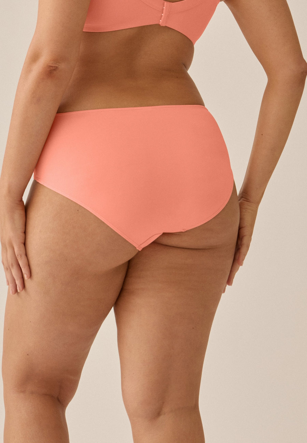 Achterzijde van vrouw die de slip met glansband in de kleur peach pink van het merk Naturana draagt