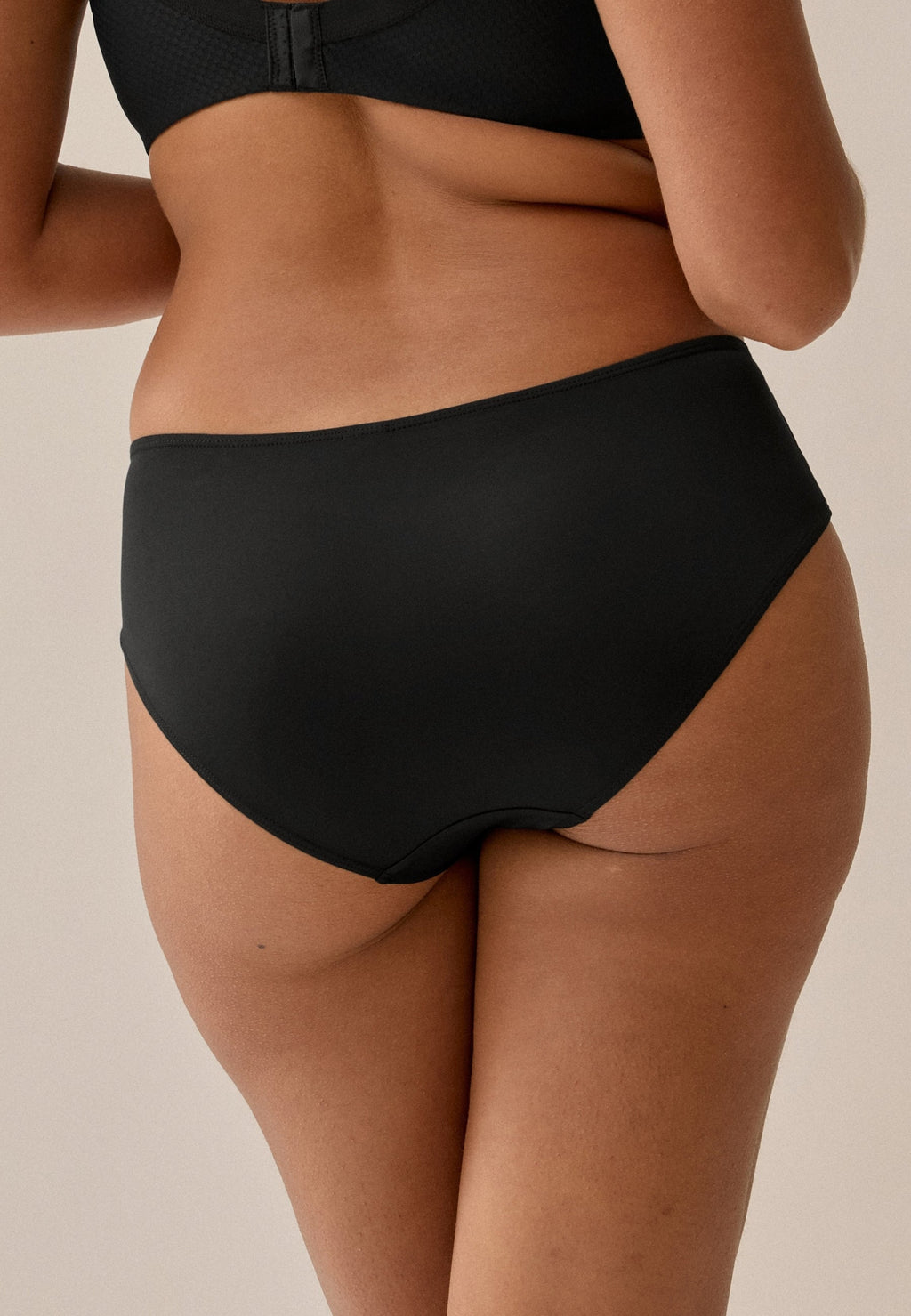 Achterzijde van vrouw die de slip met glansband in de kleur zwart van het merk Naturana draagt