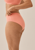 Zijde van vrouw die de slip met glansband in de kleur peach pink van het merk Naturana draagt