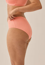 Zijde  van vrouw die de slip met glansband in de kleur peach pink van het merk Naturana draagt