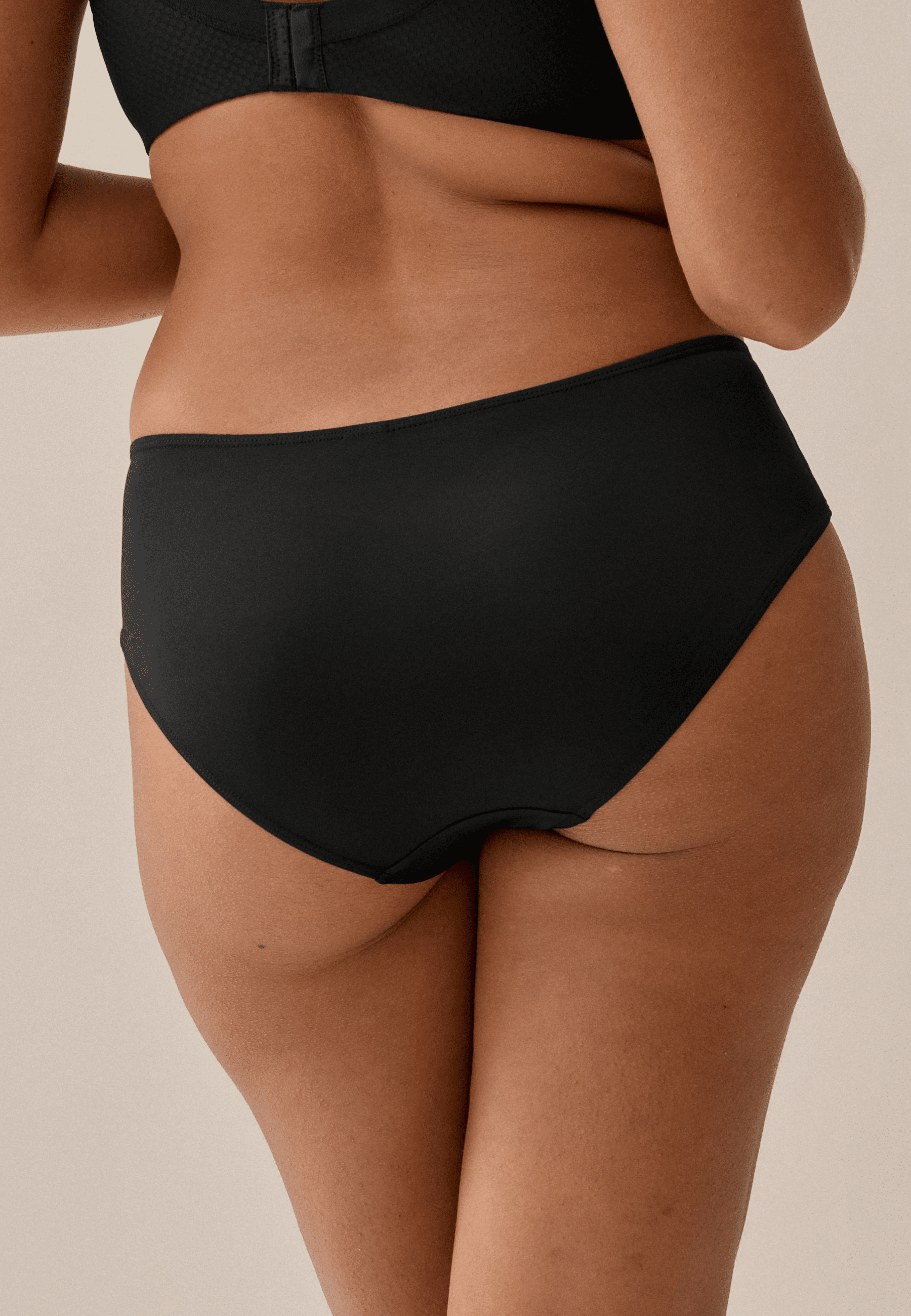 Achterzijde van vrouw die de slip met glansband in de kleur zwart van het merk Naturana draagt