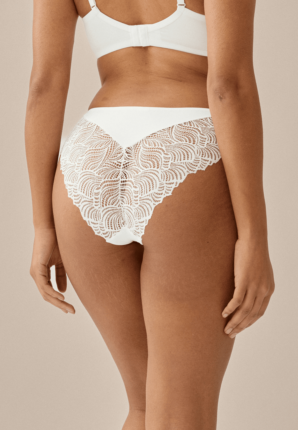 Achterzijde van vrouw die de slip met gerecycled kant in de kleur ecru van het merk Naturana draagt