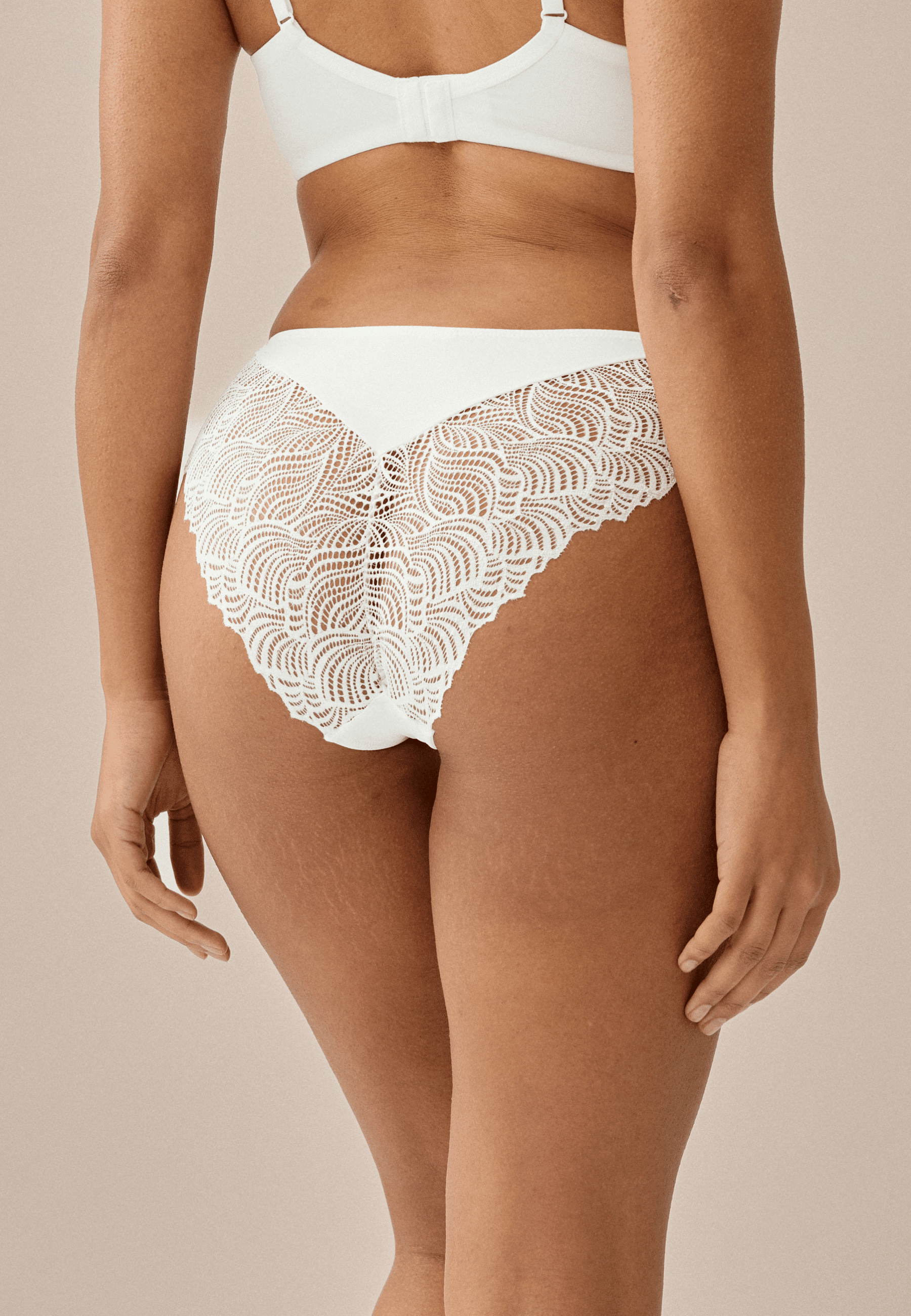 Achterzijde van vrouw die de slip met gerecycled kant in de kleur ecru van het merk Naturana draagt