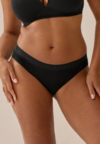 Voorzijde van vrouw die de katoenen slip met kanten rand in de kleur zwart van het merk Naturana draagt