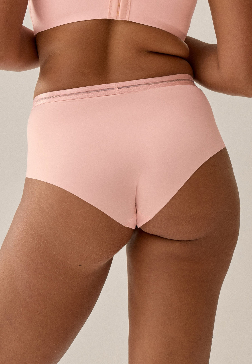 Achterzijde van vrouw die de slip met mesh detail in de kleur pink rose van het merk Naturana draagt
