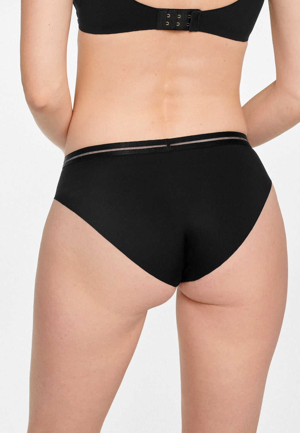 Achterzijde van vrouw die de slip met mesh detail in de kleur zwart van het merk Naturana draagt