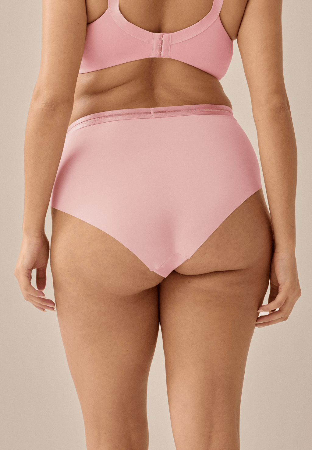 Achterzijde van vrouw die de slip met mesh detail in de kleur pink rose van het merk Naturana draagt