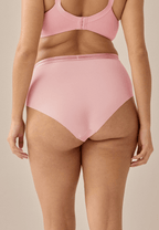 Achterzijde van vrouw die de slip met mesh detail in de kleur pink rose van het merk Naturana draagt