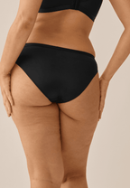 Achterzijde van vrouw die de slip in de kleur zwart van het merk Naturana draagt