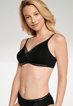 Zijde van vrouw die de soft bh met mesh detail en slip met mesh detail in de kleur zwart van het merk Naturana draagt