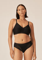 Voorzijde van vrouw die de soft bh met mesh detail en slip met mesh detail in de kleur zwart van het merk Naturana draagt