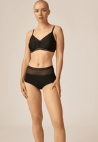 Voorzijde van vrouw die de soft bh met mesh detail en hoge slip met mesh in de kleur zwart van het merk Naturana draagt