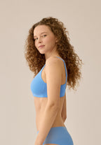 Zijde van vrouw die de soft bh met brede bandjes in de kleur marina blue van het merk Naturana draagt