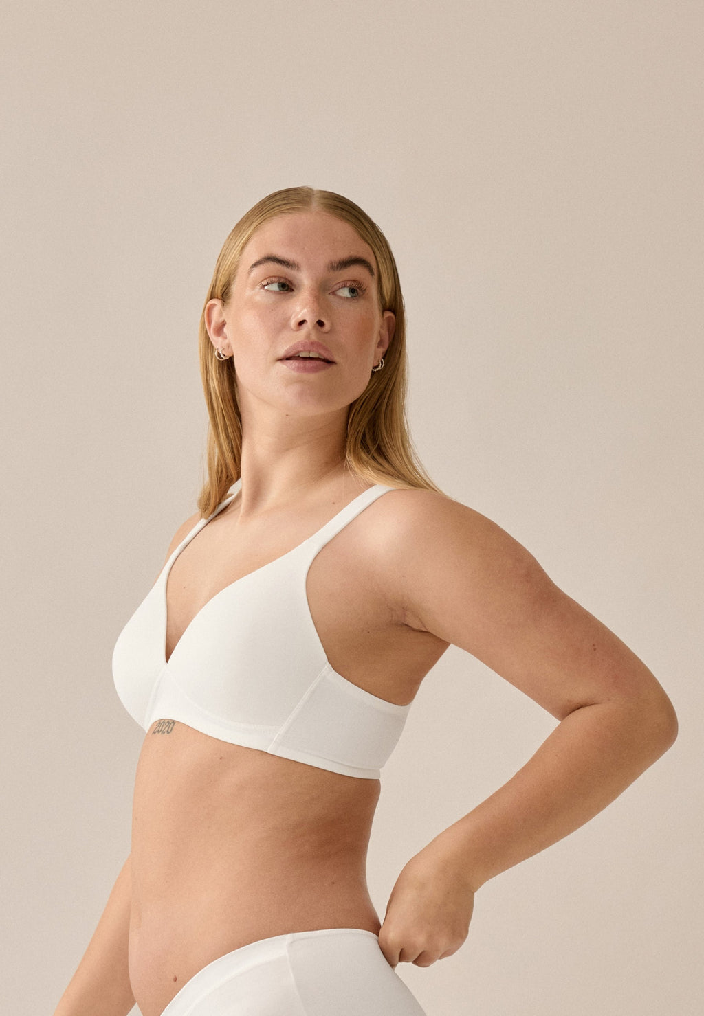 Zijde van vrouw die de soft bh met brede bandjes in de kleur ecru van het merk Naturana draagt