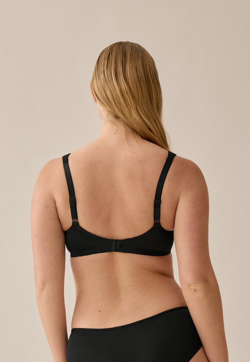 Achterzijde van vrouw die de soft bh met brede bandjes in de kleur zwart van het merk Naturana draagt