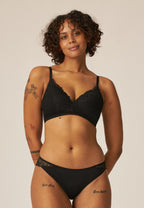 Voorzijde van vrouw die de voorgevormde soft bh met gerecycled kant en slip met gerecycled  kant in de kleur zwart van het merk Naturana draagt