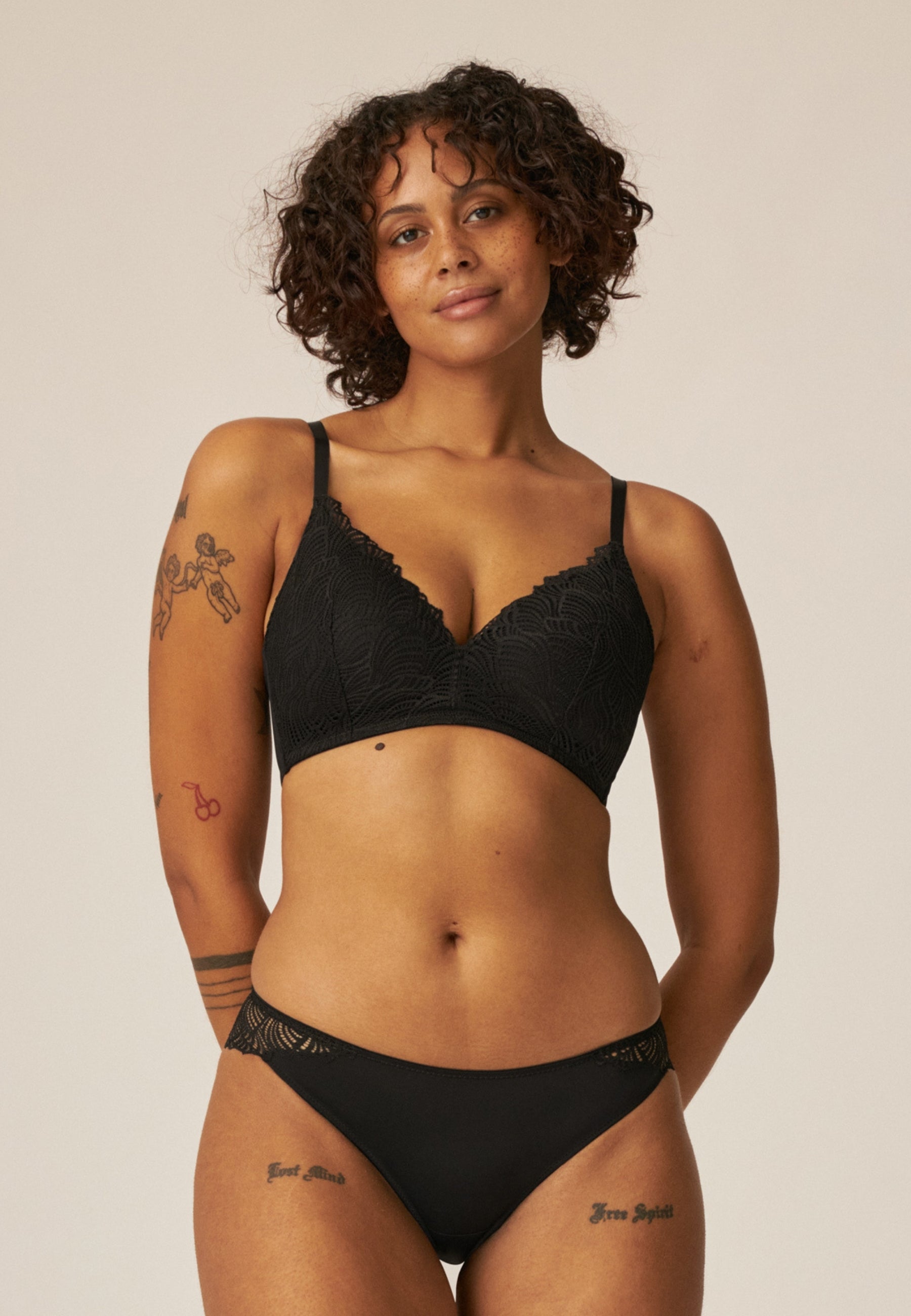 Voorzijde van vrouw die de voorgevormde soft bh met gerecycled kant en slip met gerecycled  kant in de kleur zwart van het merk Naturana draagt