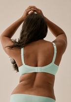 Achterzijde van vrouw die de soft bh met glansband in de kleur aquamenta van het merk Naturana draagt