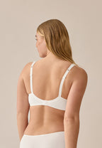 Achterzijde van vrouw die de soft bh met glansband met glansband in de kleur ecru van het merk Naturana draagt