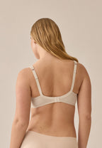 Achterzijde van vrouw die de soft bh met glansband en patroon in de kleur beige van het merk Naturana draagt