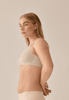 Zijde van vrouw die de soft bh met glansband en patroon in de kleur beige van het merk Naturana draagt