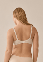 Achterzijde van vrouw die de soft bh met glansband en patroon in de kleur beige van het merk Naturana draagt