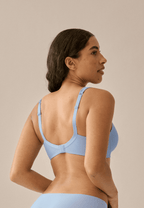 Achterzijde van vrouw die de soft bh met glansband en patroon in de kleur forever blue van het merk Naturana draagt
