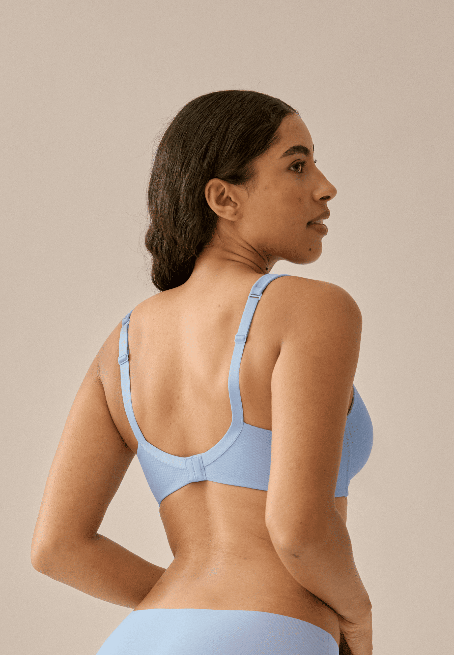Achterzijde van vrouw die de soft bh met glansband en patroon in de kleur forever blue van het merk Naturana draagt