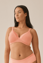 Voorzijde van vrouw die de soft bh met glansband in de kleur peach pink van het merk Naturana draagt