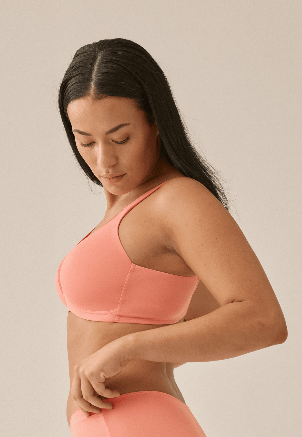 Achterzijde van vrouw die de soft bh met glansband in de kleur peach pink van het merk Naturana draagt