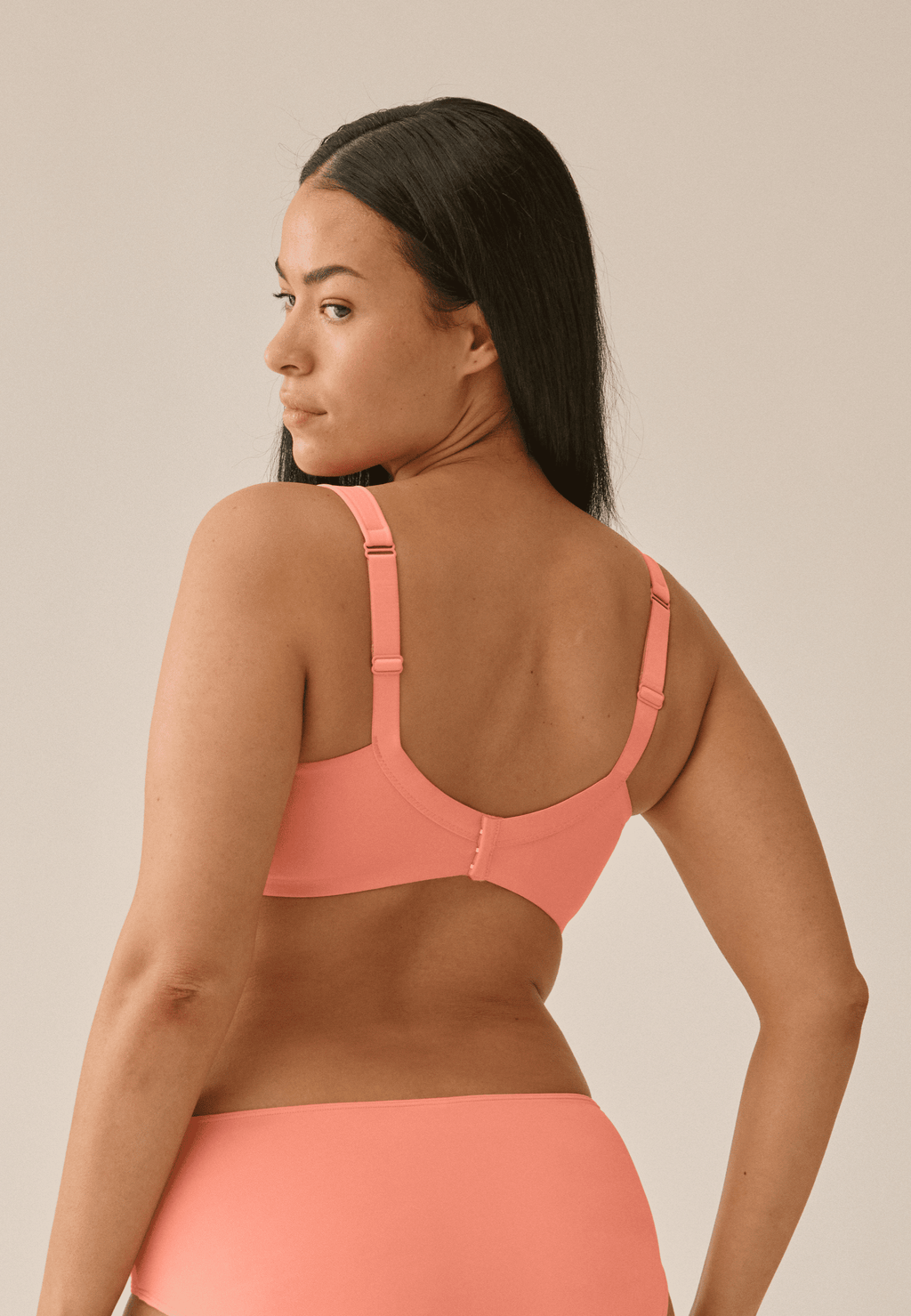 Achterzijde van vrouw die de soft bh met glansband in de kleur peach pink van het merk Naturana draagt