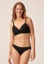 Voorzijde van vrouw die de voorgevormde soft bh met gerecycled kant en slip met gerecycled  kant in de kleur zwart van het merk Naturana draagt