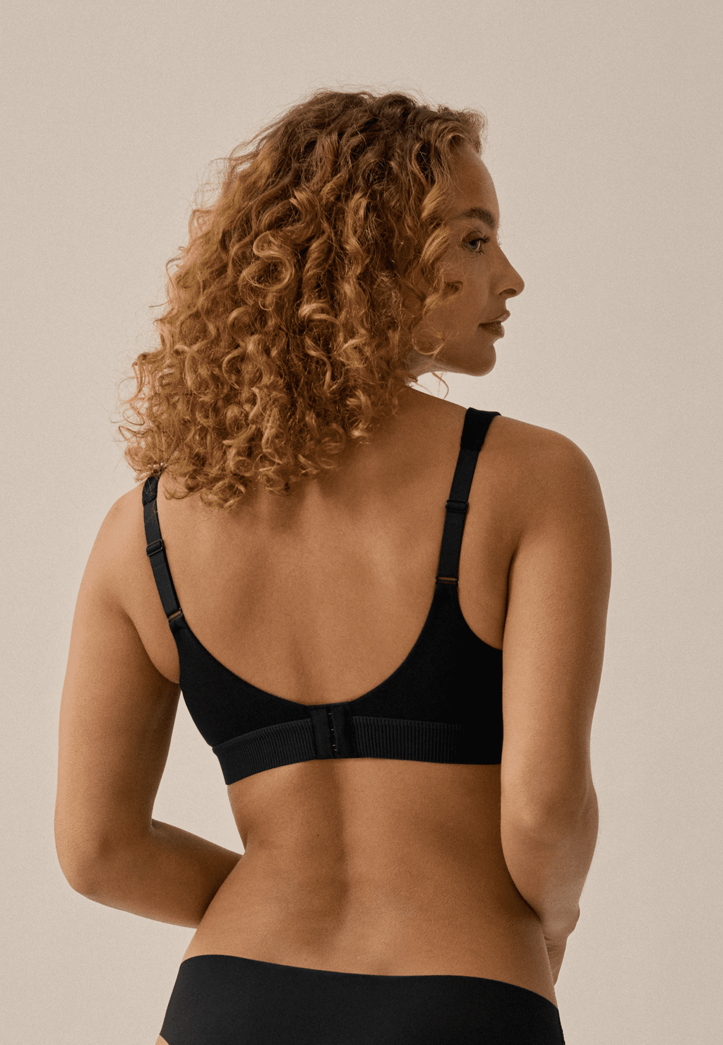Achterzijde  van vrouw die de katoenen soft bh in de kleur zwart van het merk Naturana draagt 