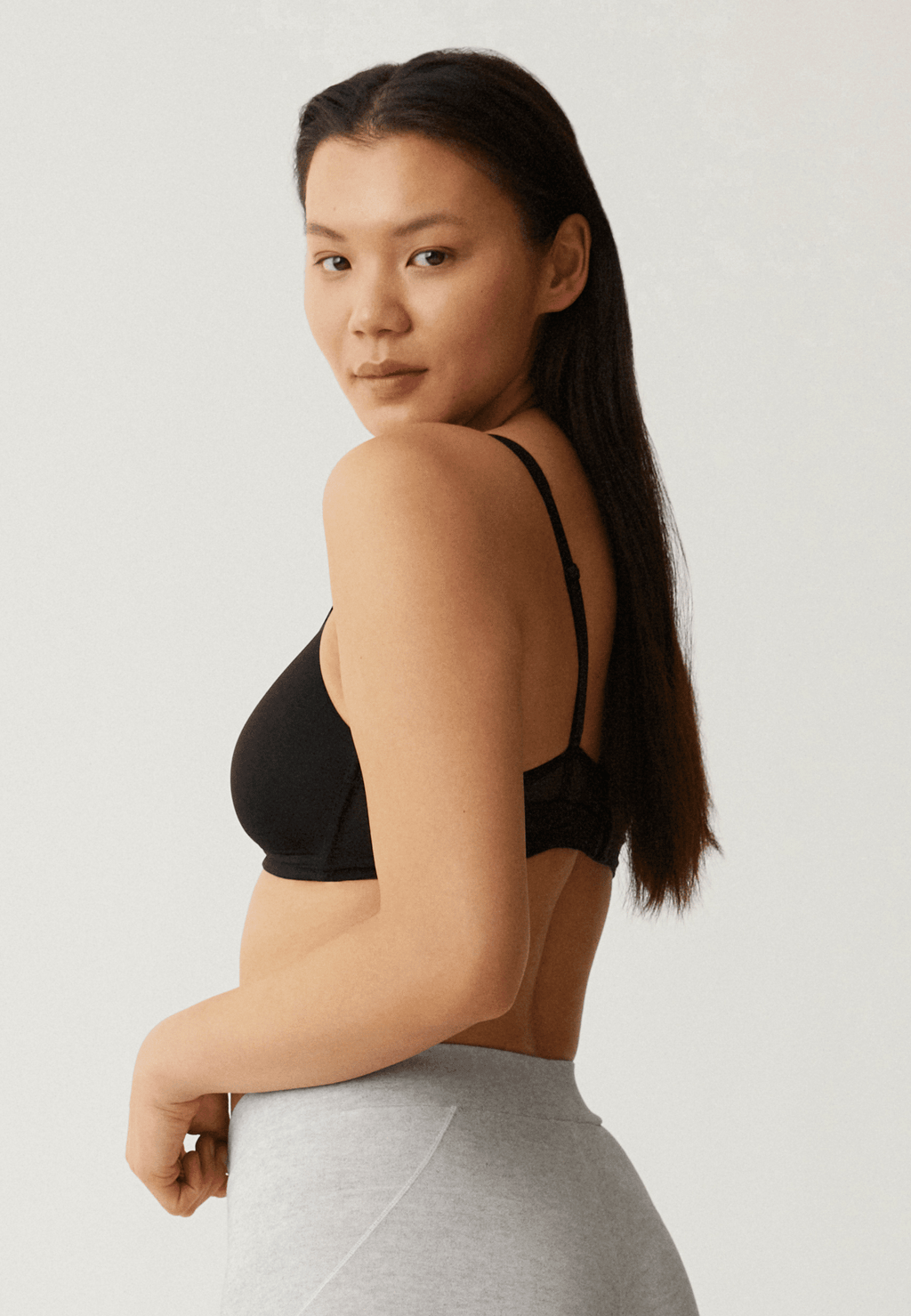 Zijde van vrouw die de soft bh met mesh bandjes in de kleur zwart van het merk Naturana draagt