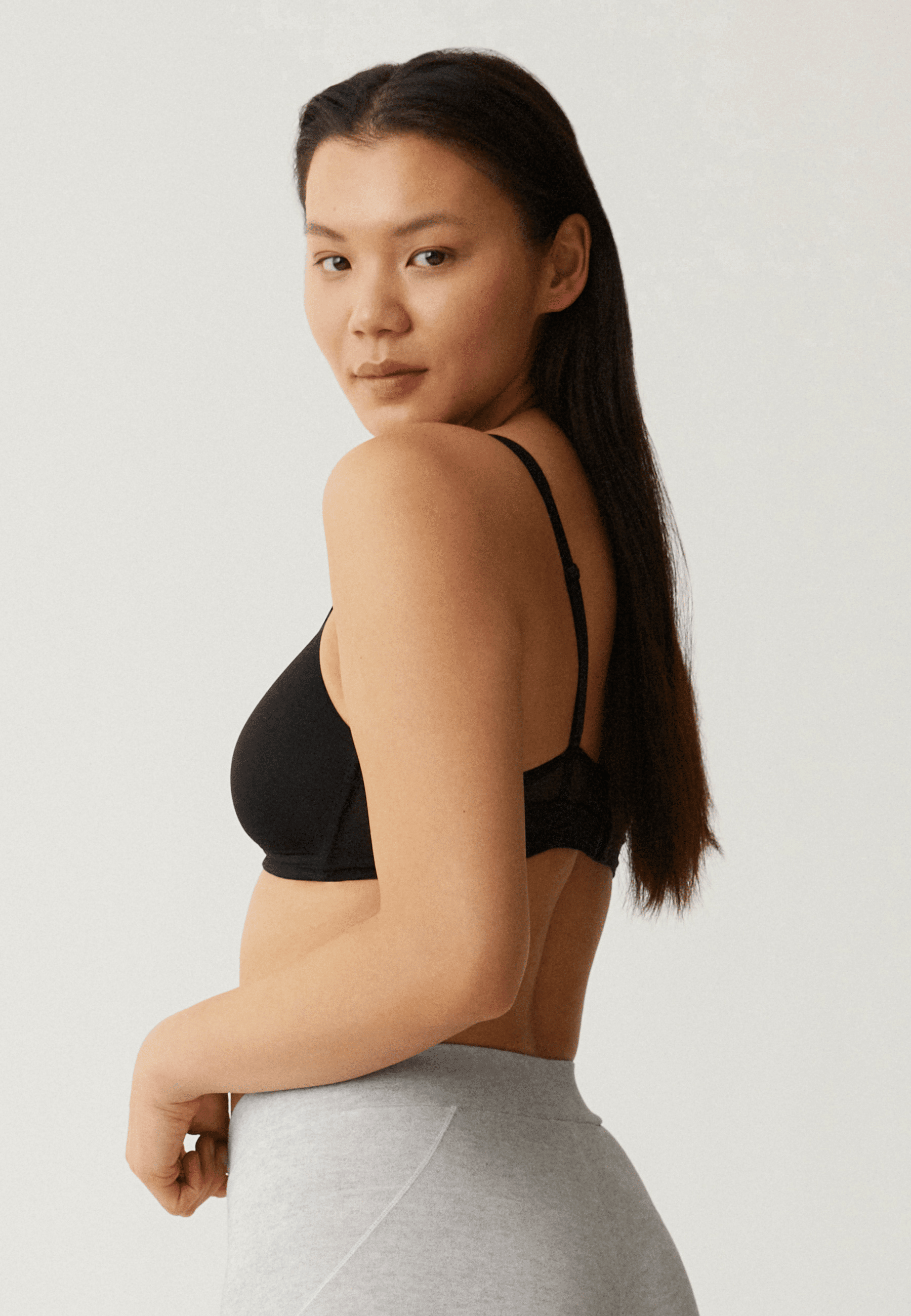 Zijde van vrouw die de soft bh met mesh bandjes in de kleur zwart van het merk Naturana draagt