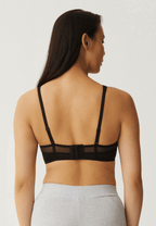Achterzijde van vrouw die de soft bh met mesh bandjes in de kleur zwart van het merk Naturana draagt