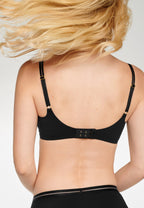 Achterzijde van vrouw die de soft bh en slip met mesh detail in de kleur zwart van het merk Naturana draagt