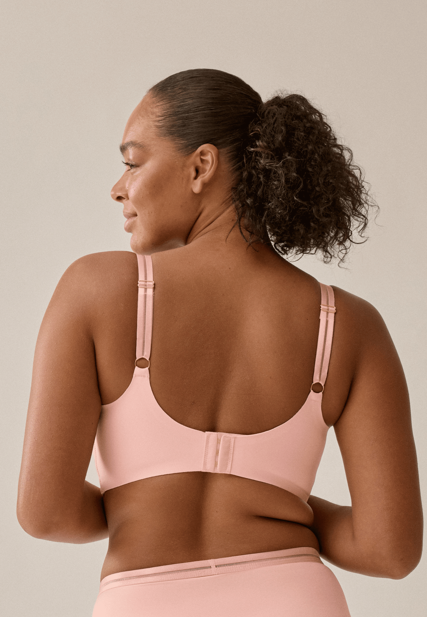 Achterzijde van vrouw die de soft bh met mesh detail in de kleur pink rose van het merk Naturana draagt