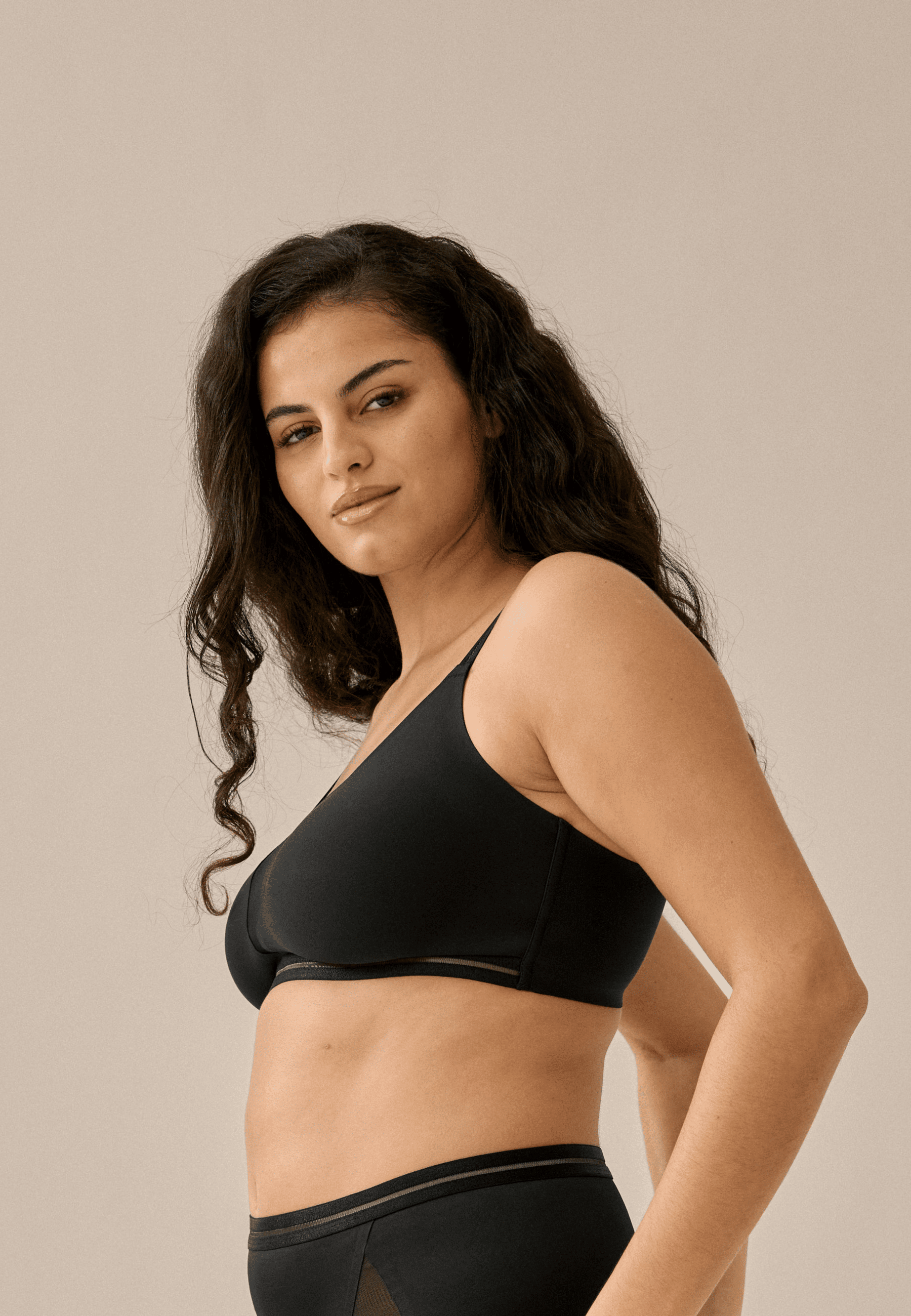 Zijde van vrouw die de soft bh met mesh detail in de kleur zwart van het merk Naturana draagt