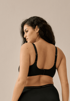Achterzijde van vrouw die de soft bh met mesh detail in de kleur zwart van het merk Naturana draagt