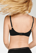 Achterzijde van vrouw die de soft bh met mesh detail in de kleur zwart van het merk Naturana draagt