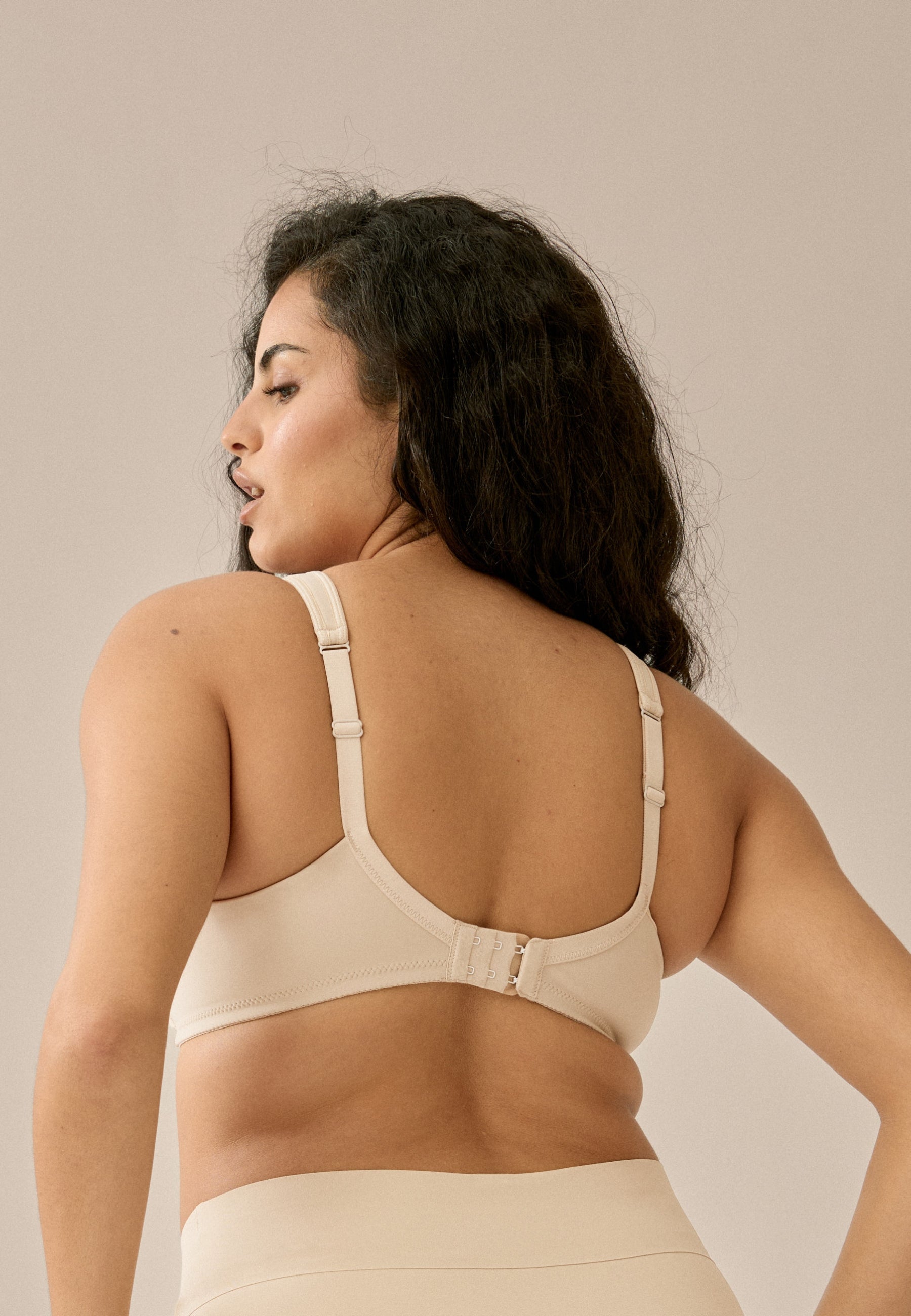 Achterzijde van vrouw die de soft bh met meshrand in de kleur beige van het merk Naturana draagt